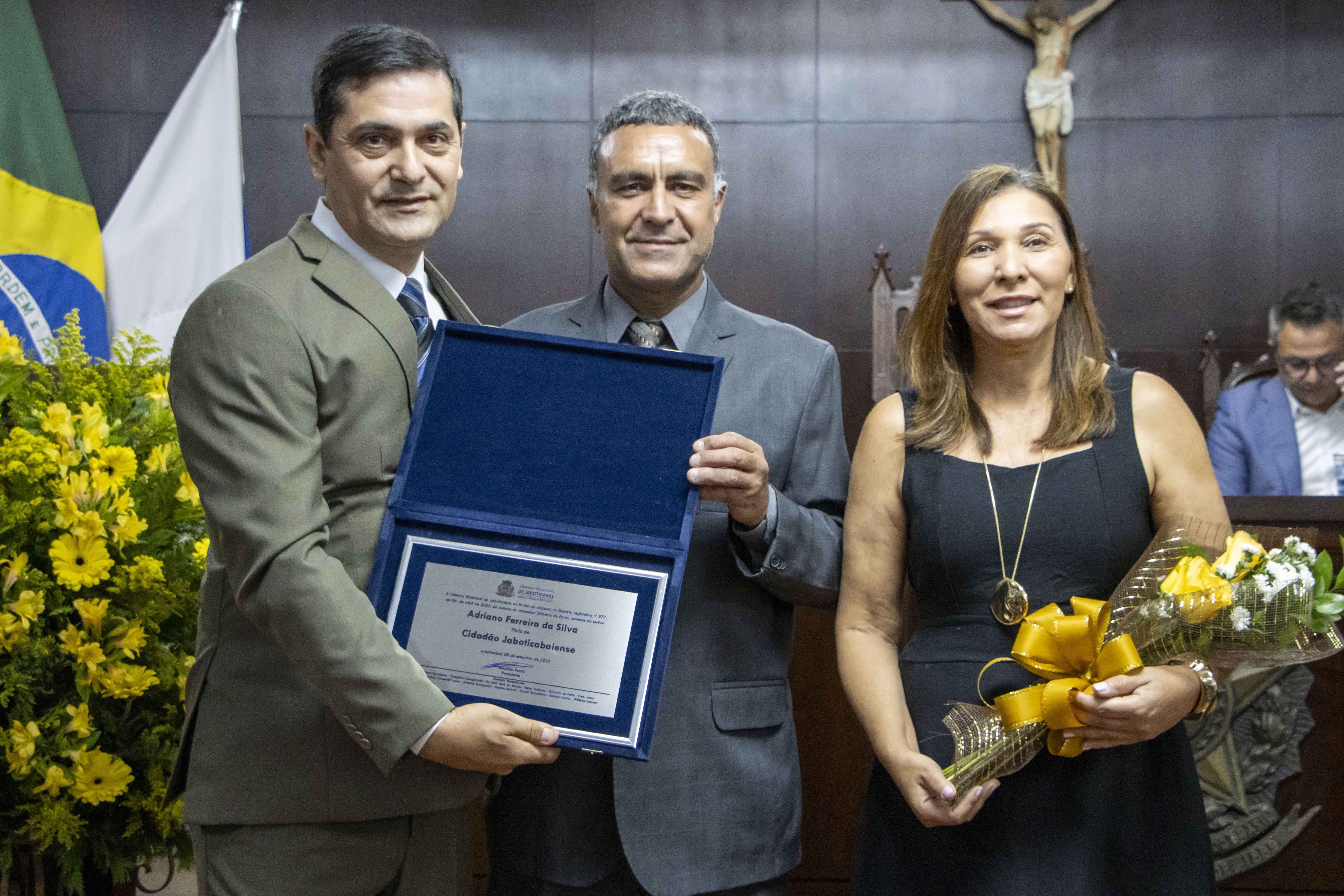 Adriano Ferreira da Silva, ao lado da esposa Eliene de Souza Santos Ferreira da Silva, recebe o Título de Cidadão Jaboticabalense das mãos do vereador Gilberto de Faria em sessão solene realizada no dia 08/09/2025.